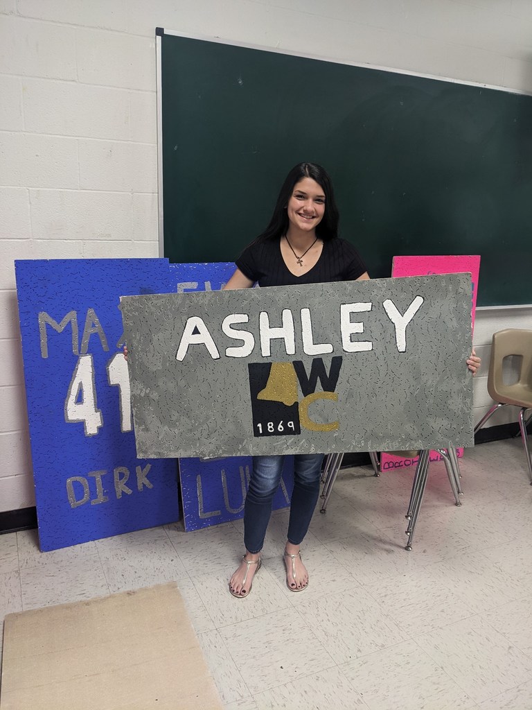 Ashley holds her ceiling tile with the Weatherford College logo on it.