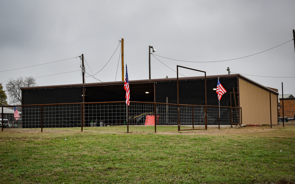 Ag Barn (weatherproofed) and new fence built by welding students, adorned by American Flags